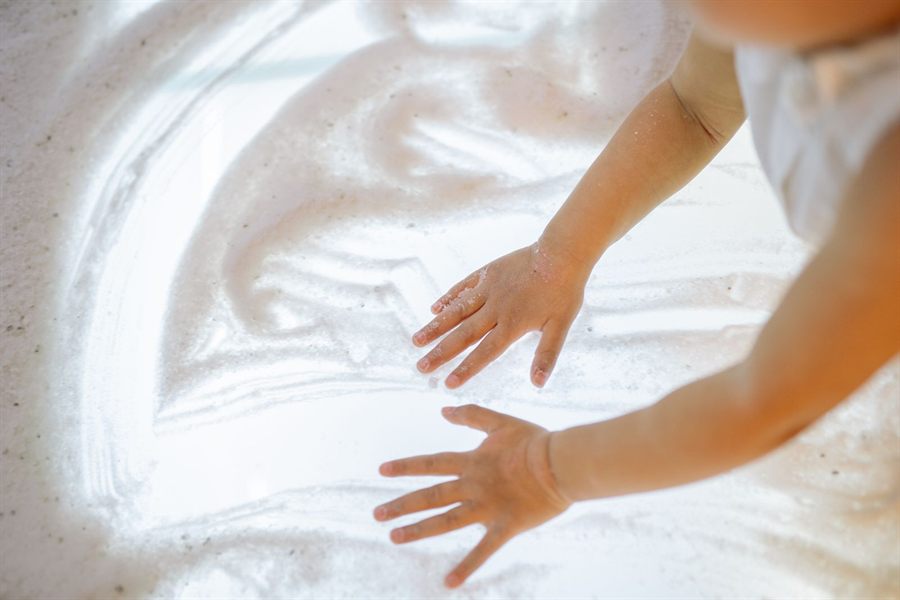 Small hands playing in soft sand