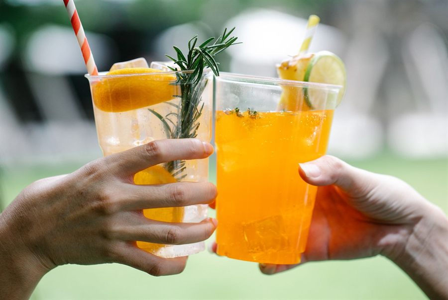 Two hands raising glasses of alcohol-free fruit drinks
