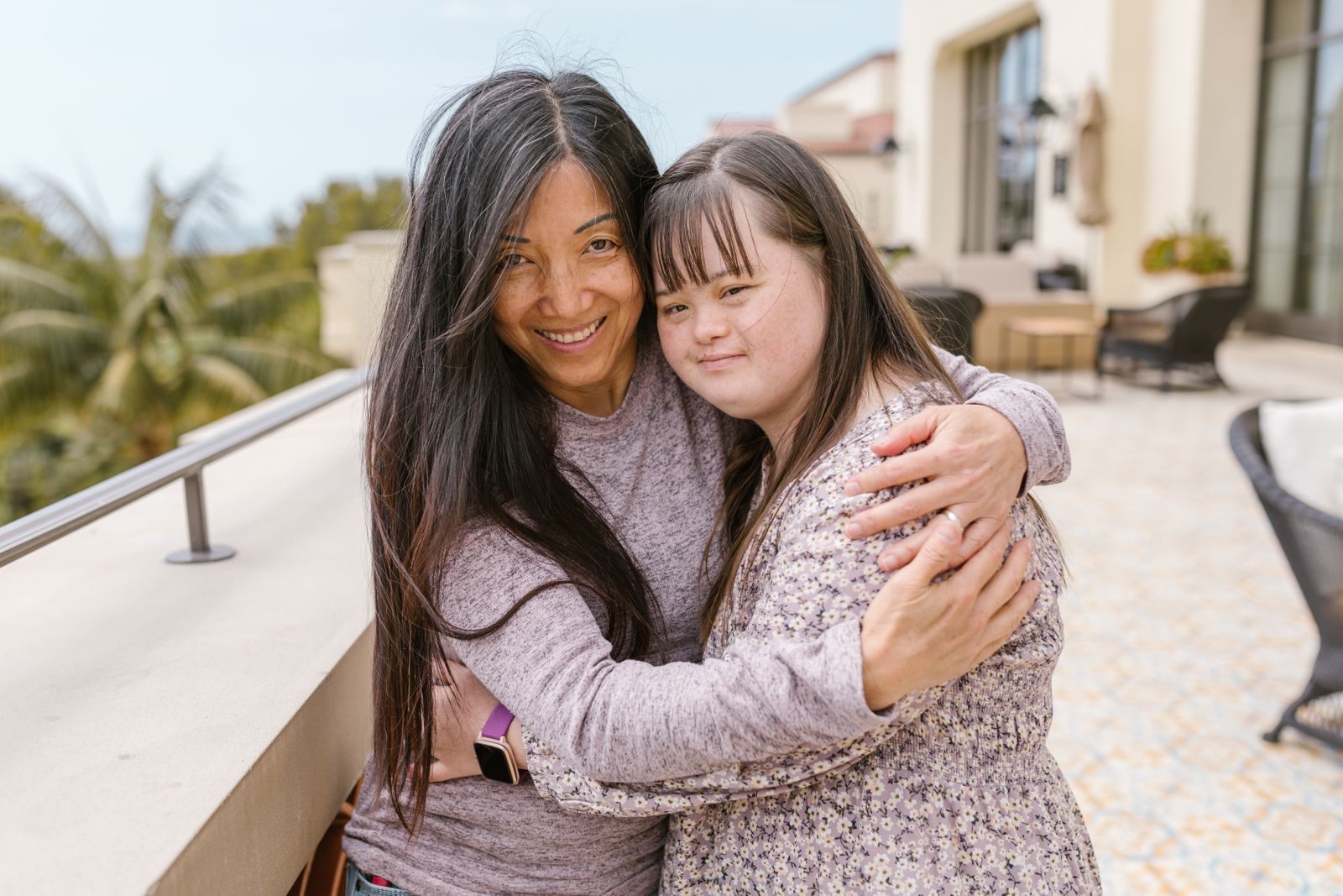 Mother and daughter with Down syndrome hugging on a sunny terrace, the kind of family special needs cruises serve