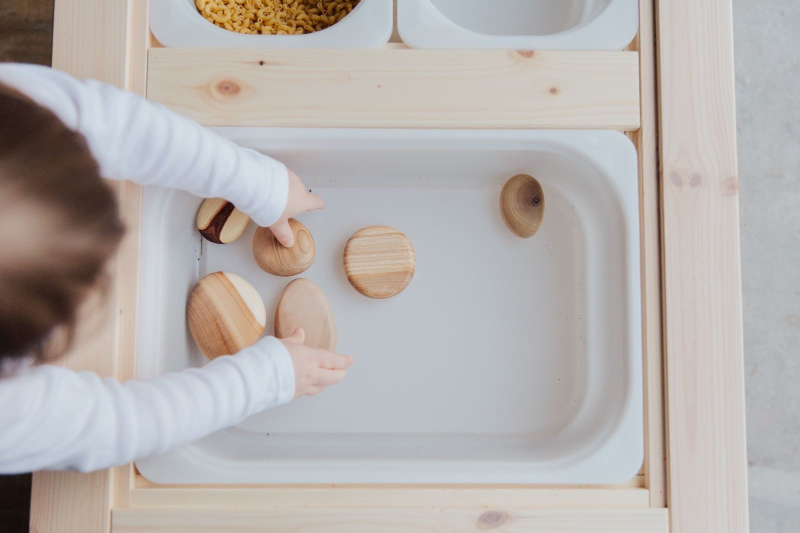 Child playing with wooden shapes in a sensory tray, part of choosing the best cruise line for special needs kids